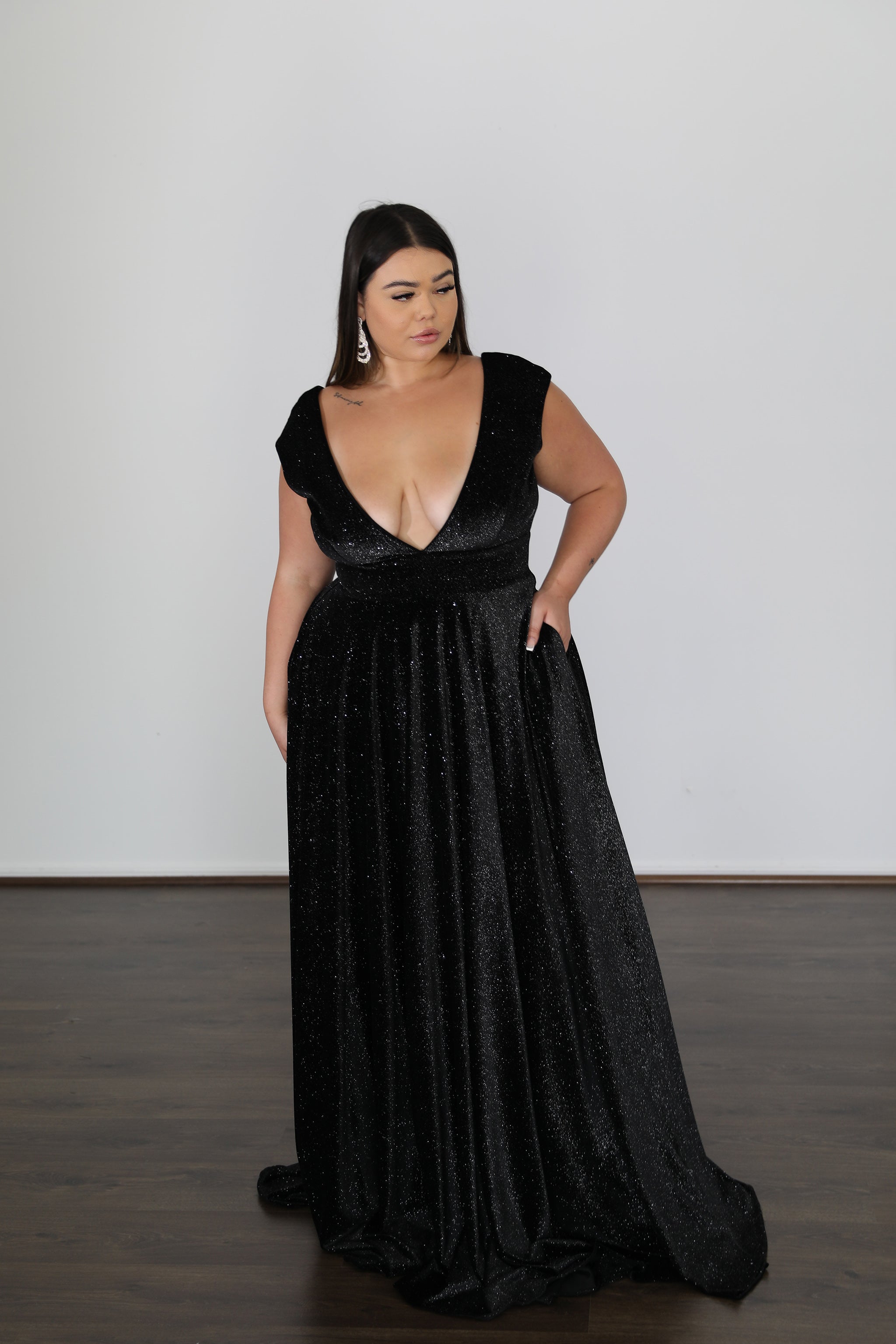 model with her hand in the pocket of her black flowing formal dress